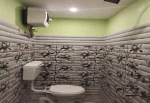 a bathroom with a toilet and flowers on the wall at RD Residency Hotel at IIT Gate Kanpur in Kānpur