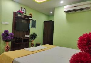 a bedroom with a bed and a television and flowers at RD Residency Hotel at IIT Gate Kanpur in Kānpur