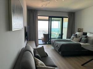Un dormitorio con una cama y un sofá y un balcón. en Baltic Infinity Sea&Beach Międzyzdroje, en Międzyzdroje