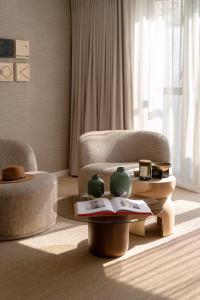 een woonkamer met een stoel en een tafel met vazen erop bij Satori Lodge by Bliss Collection in Kaapstad