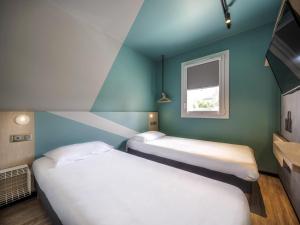two beds in a room with blue walls and a window at ibis budget Forbach Centre in Forbach