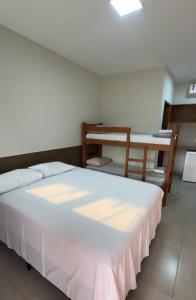 une chambre avec un lit blanc et un bureau dans l'établissement Camping Rio Formoso, à Bonito