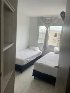 two beds in a small room with a window at Suite Vista Azul Ricaurte in Ricaurte