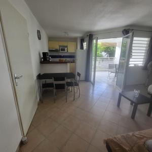 a living room with a table and chairs and a kitchen at Appartement Personnes à Mobilité Réduite in Sainte-Anne +2 photos
