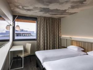 a hotel room with two beds and a window at ibis Lyon Est Meyzieu in Meyzieu