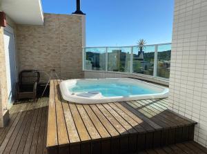 ボンビーニャスにあるCobertura com jacuzzi 2 minutos da praiaの家のデッキにジャグジータブが備わります。