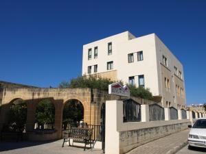 a building on a street with a bench in front of it at Rivotorto Retreat House in Birkirkara