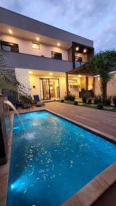 une grande piscine bleue devant une maison dans l'établissement Casa de 3 quartos em Franca - Piscina aquecida, banheira, conforto e lazer, à Franca