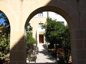 an archway leading to a building with chairs and trees at Rivotorto Retreat House in Birkirkara