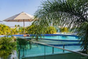 a swimming pool with an umbrella and a table and chairs at Star Hotel in Jericoacoara