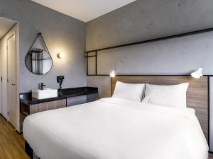 a bedroom with a large white bed and a sink at Ibis Aruja in Arujá