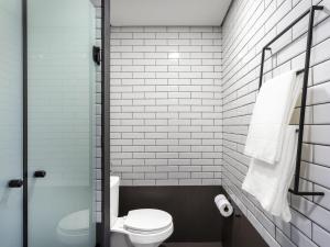 a small bathroom with a toilet and white tiles at Ibis Aruja in Arujá