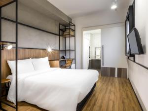 阿鲁雅Ibis Aruja的卧室里有一张白色的大床和一台电视