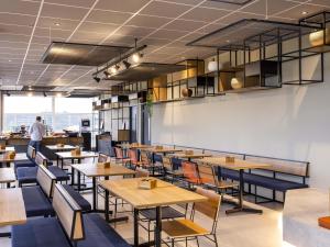 a restaurant with wooden tables and blue chairs at Ibis Aruja in Arujá