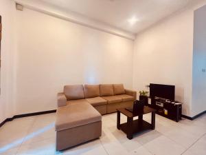 a living room with a couch and a tv at Ohana Beach in Tangalle