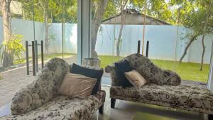 two chairs and a couch in a room with a window at Villa Mana - Colombo, Sri Lanka in Kirillapone