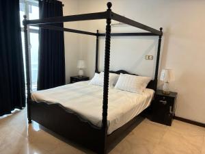 a bedroom with a black canopy bed with white sheets at Villa Mana - Colombo, Sri Lanka in Kirillapone