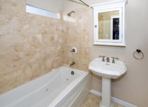 y baño con lavabo, bañera, lavabo blanco y espejo. en Prime Spanish Villa in West Hollywood, en Los Ángeles