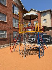 a playground with a play equipment in front of a building at Modern Style Apartments, An Escape From The City in Pretoria