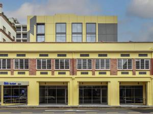 a yellow building with windows on a street at ibis budget Singapore Gold in Singapore
