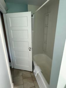 a bathroom with a white door and a bath tub at Midstream Manor Unit 6, Studio in St. John's