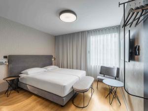 Un dormitorio con una gran cama blanca y una silla. en ibis Styles Ljubljana Centre, en Liubliana