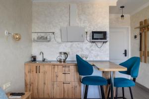 a kitchen with a wooden table and blue chairs at ЖК Арбат в Золотом квадрате Студия in Almaty