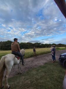 a man riding a white horse on a dirt road at Casas del Arroyo in Chapadmalal