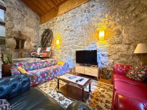 a living room with a couch and a tv at Casa Museu Lagar de Azeite in Terras de Bouro