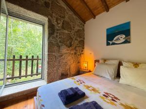 a bedroom with a bed and a large window at Casa Museu Lagar de Azeite in Terras de Bouro