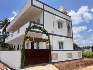 a white house with a red gate and an arch at The coconest Kinathukadavu, Coimbatore in Kinattukkadavu