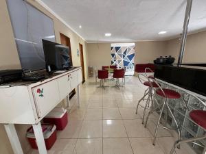 a living room with a television and a table with chairs at Chacará Village do Rio Ouro in Conde