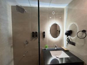 a bathroom with a sink and a shower with a mirror at Zoneout Stays Omaxe Hazratganj in Lucknow