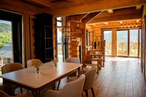 a dining room with a table and chairs and windows at Magura Resort in Yablunytsya