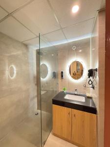 a bathroom with a sink and a glass shower at Zoneout Stays Omaxe Hazratganj in Lucknow