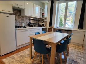 a kitchen with a wooden table and blue chairs at VILLA ILIXON - Appartements privés proche du centre de Luchon, parking, billard, jardin in Luchon