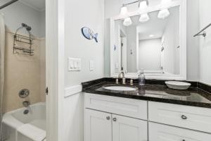 ein weißes Badezimmer mit Waschbecken und Spiegel in der Unterkunft Lagoon Villa 19 - Lagoon Lifestyle! Center of Wild Dunes! in Isle of Palms