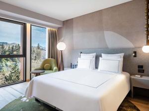 a bedroom with a white bed and a large window at Swissôtel Tbilisi in Tbilisi City