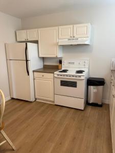 a kitchen with white cabinets and a white stove and refrigerator at Airport Manor Unit 2, 2 Bedroom Apartment in Torbay