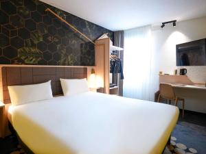 a bedroom with a large white bed and a desk at ibis Styles Strasbourg Nord Palais des Congrès in Schiltigheim