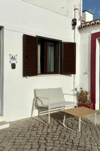 ein weißer Stuhl und ein Tisch vor einem Gebäude in der Unterkunft Casinha d'Adélia in Aljezur + 10 Fotos