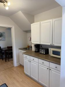 a kitchen with white cabinets and a table with a microwave at Airport Manor Unit 3, 2 Bedroom Apartment in Torbay