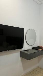 TV de pantalla plana colgada en una pared con espejo en ارجان نجد للوحدات المخدومه, en Al Nairyah