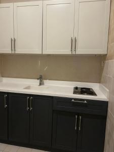 una cocina con armarios en blanco y negro y fregadero en ارجان نجد للوحدات المخدومه, en Al Nairyah