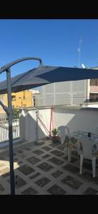 a patio with a table and chairs under a blue umbrella at Casetta Silvia in Brindisi