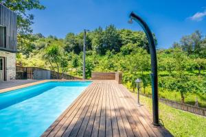 a swimming pool with a wooden deck next to a house at Moinhos do Coto in Vila Verde
