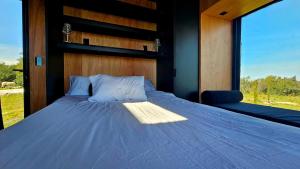 un letto in una camera con una grande finestra di NEW! Casa de campo con diseño - Casa Armonia Uruguay a Aiguá
