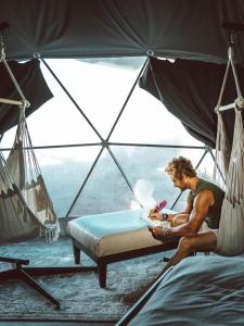 a man sitting on a bed in a tent at Rum Monet in Disah +4 photos