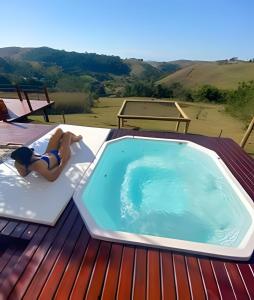 a woman laying on a chair next to a swimming pool at Chalesunset in Santa Isabel