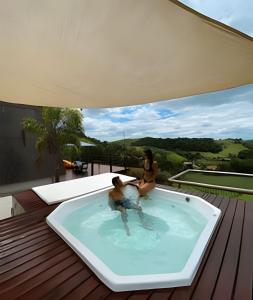 two women sitting in a hot tub on a deck at Chalesunset in Santa Isabel +49 photos